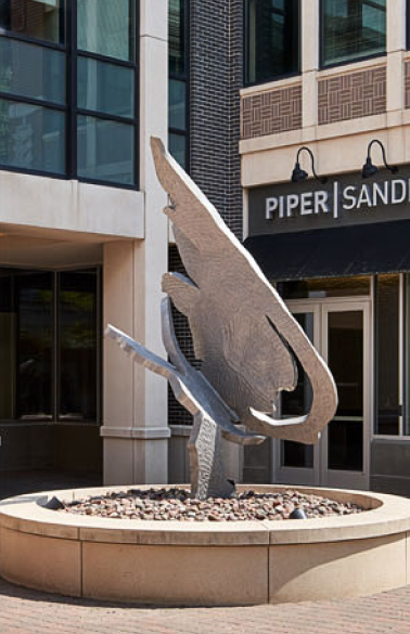 a sculpture of a bird on a pedestal in front of a building.